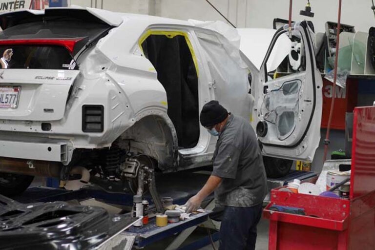 A Tony's Body Shop technician working on a stripped-down vehicle during a collision teardown